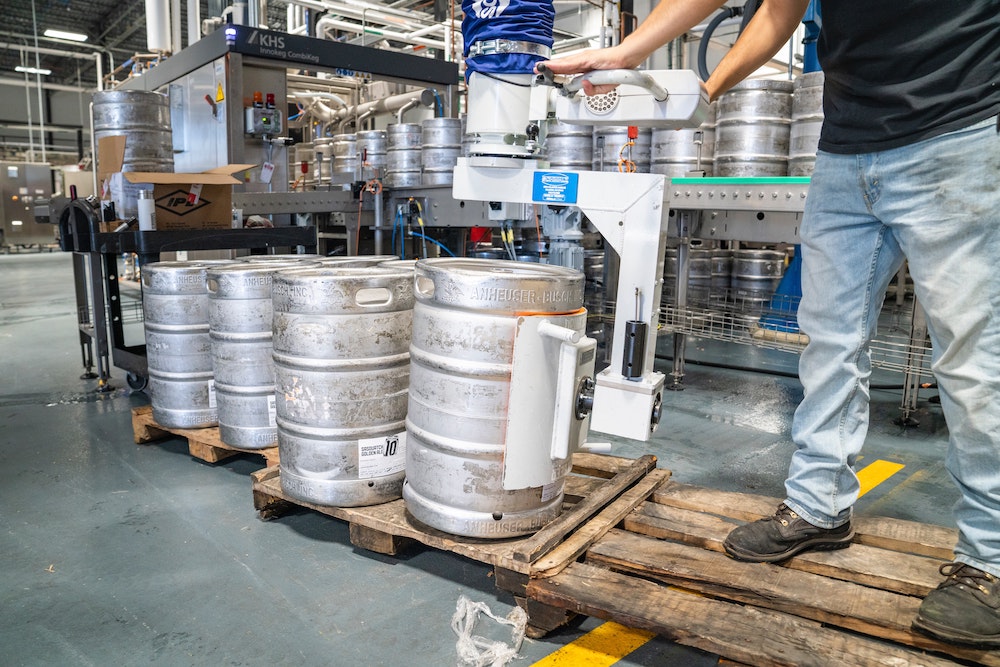 Ergonomic training in the workplace, showing a man working with heavy kegs on pallets.
